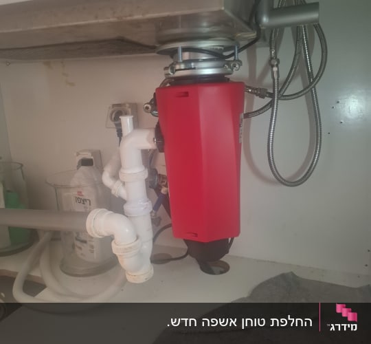 מתקן אדום מתחת לכיור עם צינורות ואביזרי אינסטלציה